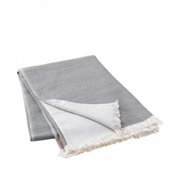 Soft gray and white fringed blanket folded on a black background.