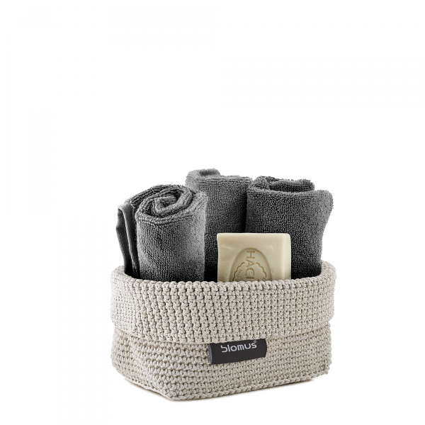 Neatly arranged gray towels and soap in a stylish woven basket.
