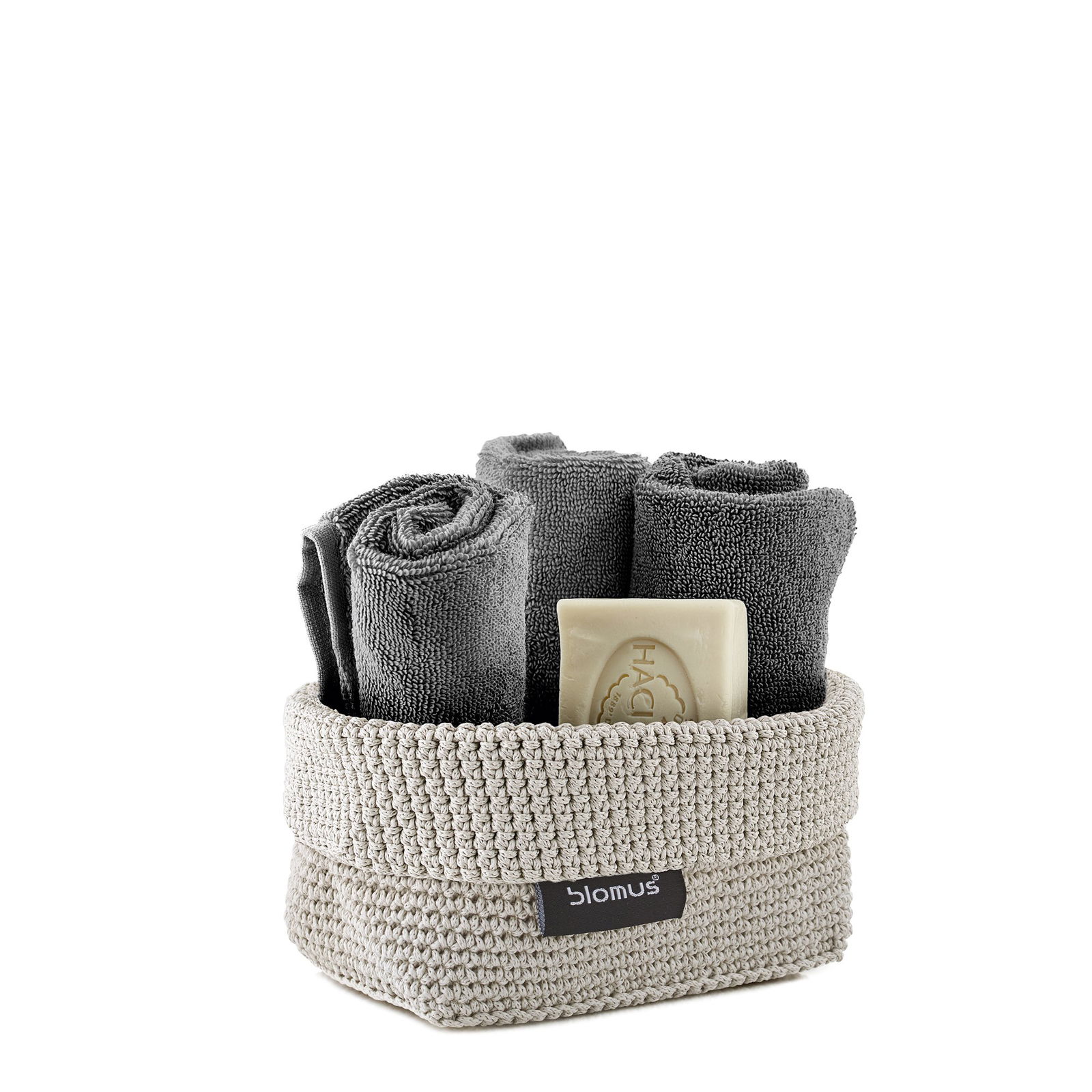 Neatly arranged gray towels and soap in a stylish woven basket.