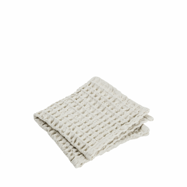 Strukturiertes cremefarbenes Deckchen, ordentlich gefaltet auf einem schwarzen Hintergrund, ideal zum Einkuscheln.