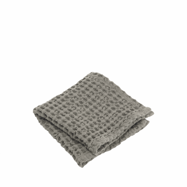 Gefaltete weiche graue Waffelstrickdecke auf schwarzem Hintergrund.