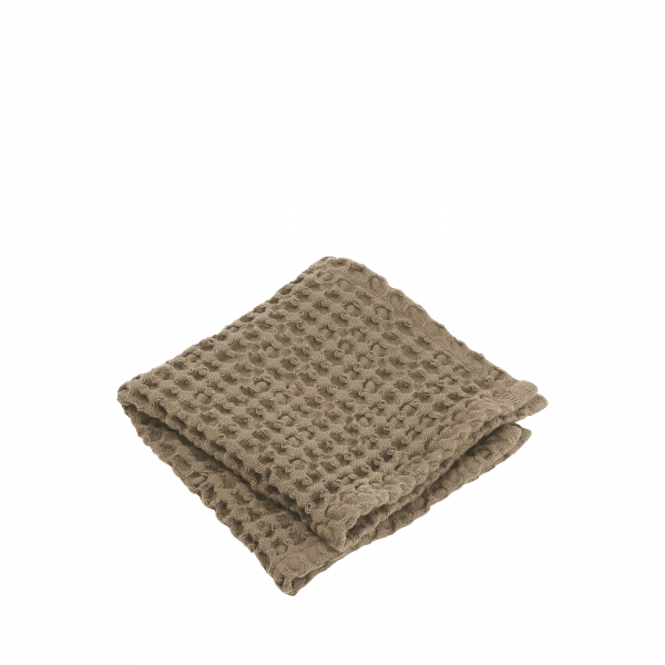 Weiche, strukturierte beige Decke ordentlich auf einem weißen Hintergrund gefaltet.