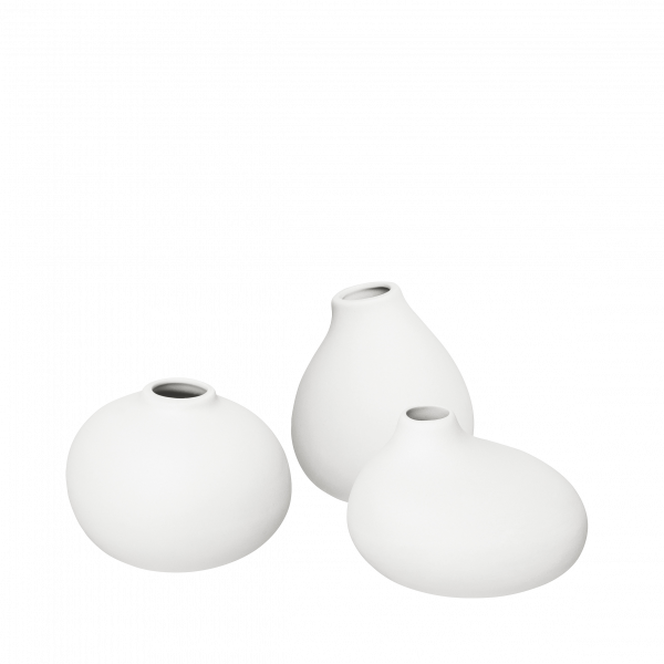 Three elegant white vases in modern shapes on a black background.