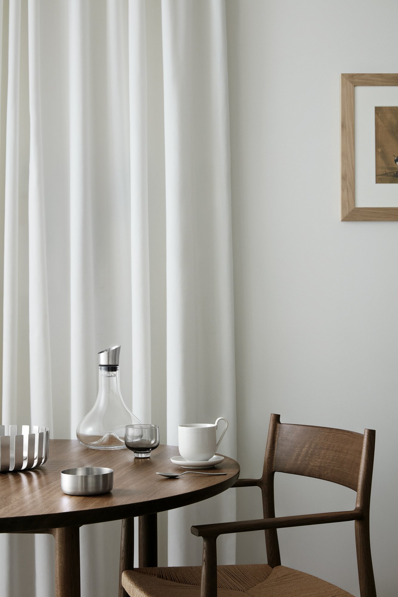 Elegant dining setting with a wooden table, white curtains, and stylish glassware.