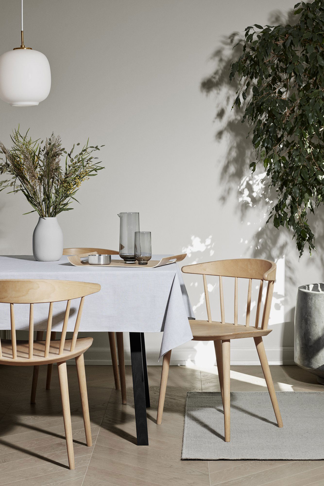 Gemütliches Esssetup mit einem Tisch, Holzbänken und einer Vase mit Blumen in sanfter Beleuchtung.