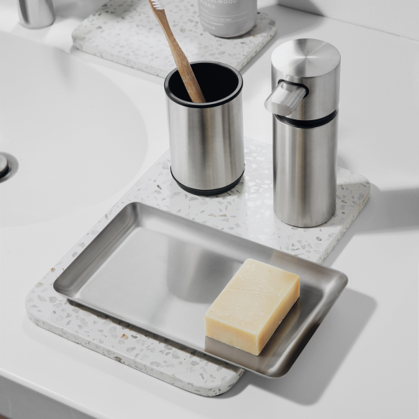 Stylische Badezimmeraccessoires, einschließlich einer Seifenschale, einem Spender und einem Zahnbürstenhalter auf einer Arbeitsplatte.