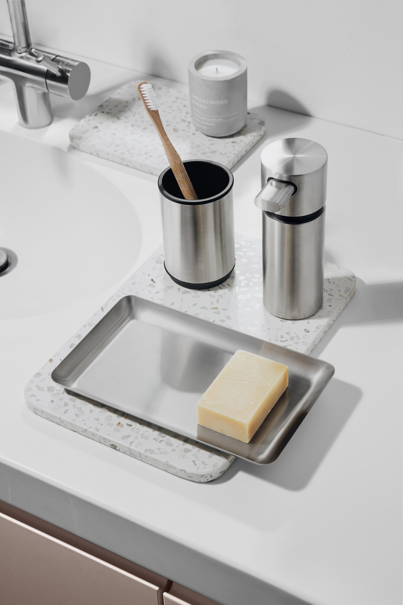 Stylische Badezimmeraccessoires, einschließlich einer Seifenschale, einem Spender und einem Zahnbürstenhalter auf einer Arbeitsplatte.