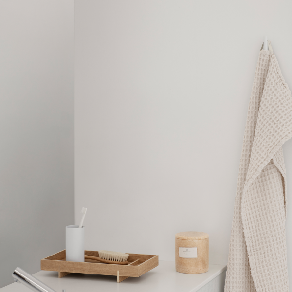 Minimalist bathroom decor featuring a wooden tray, a toothbrush holder, and a cozy towel.