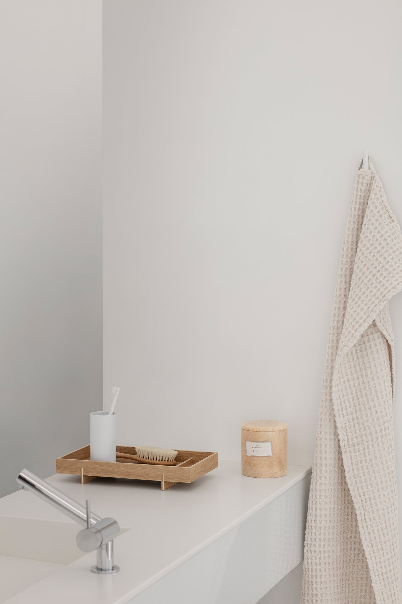 Minimalist bathroom decor featuring a wooden tray, a toothbrush holder, and a cozy towel.