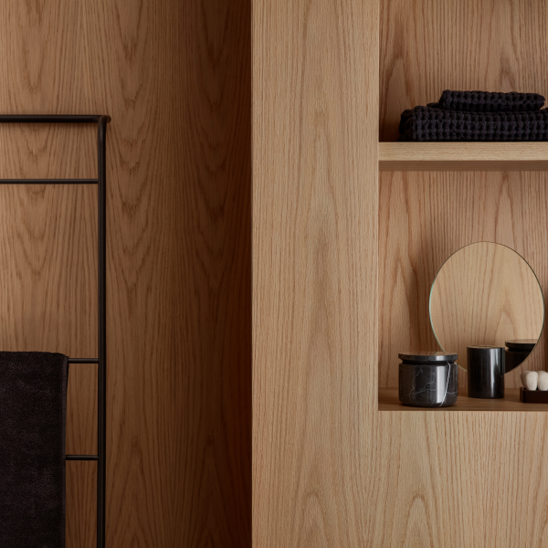 Modern bathroom decor featuring wooden panels, towels, and minimalist accessories.