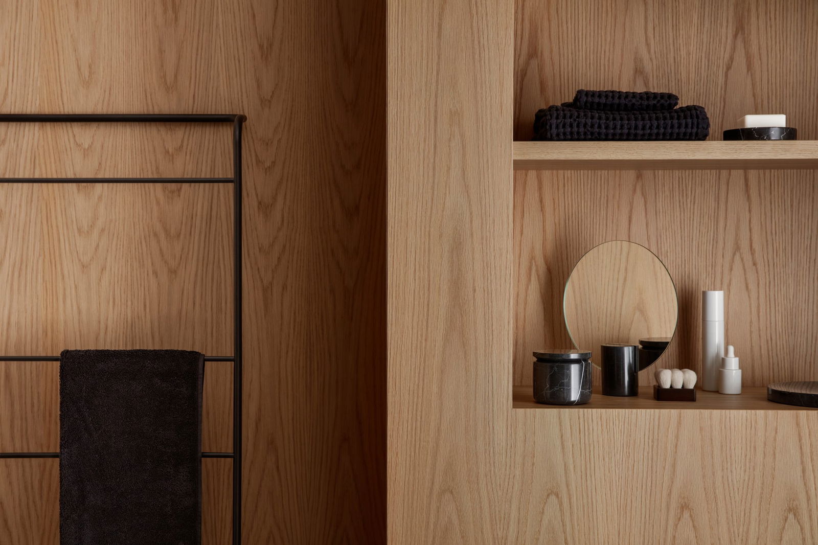 Modern bathroom decor featuring wooden panels, towels, and minimalist accessories.