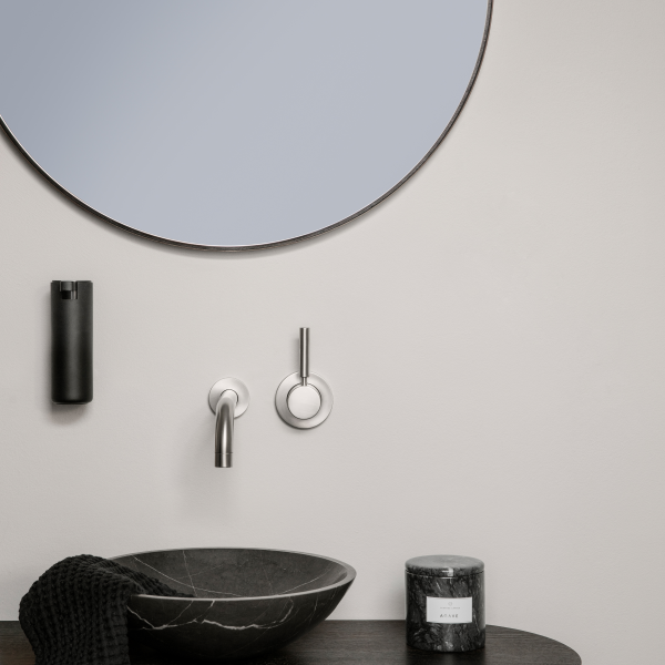 Modern bathroom decor with a sleek black sink, round mirror, and stylish accessories.