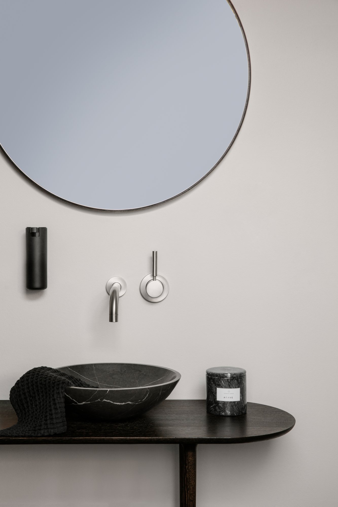 Modern bathroom decor with a sleek black sink, round mirror, and stylish accessories.
