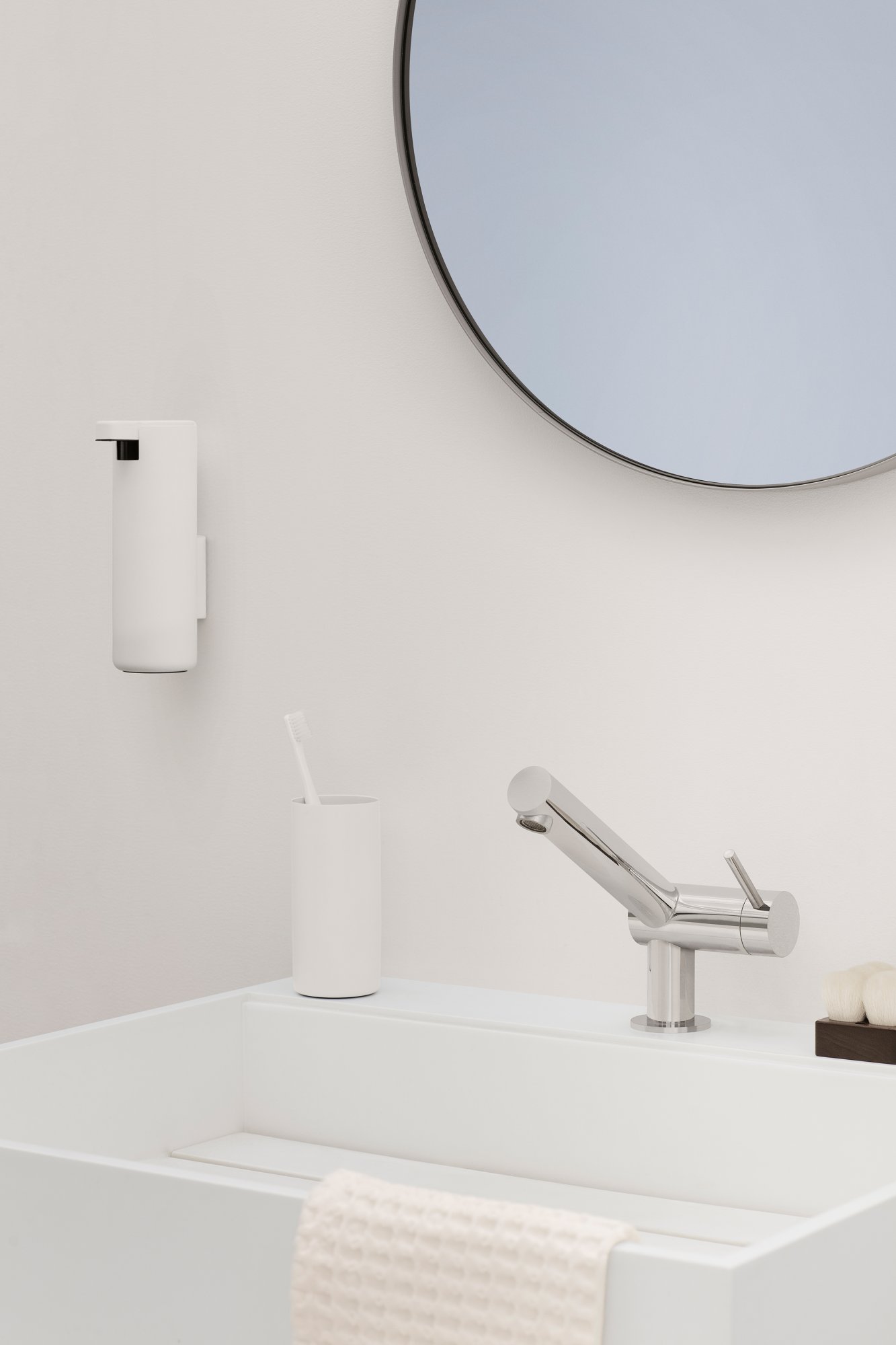 Modern bathroom setting with sleek faucet, mirror, and minimalist toiletries holder.