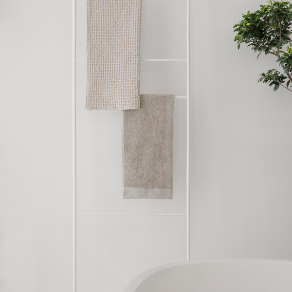 Neutral-toned towels hanging in a modern bathroom with minimalist decor.