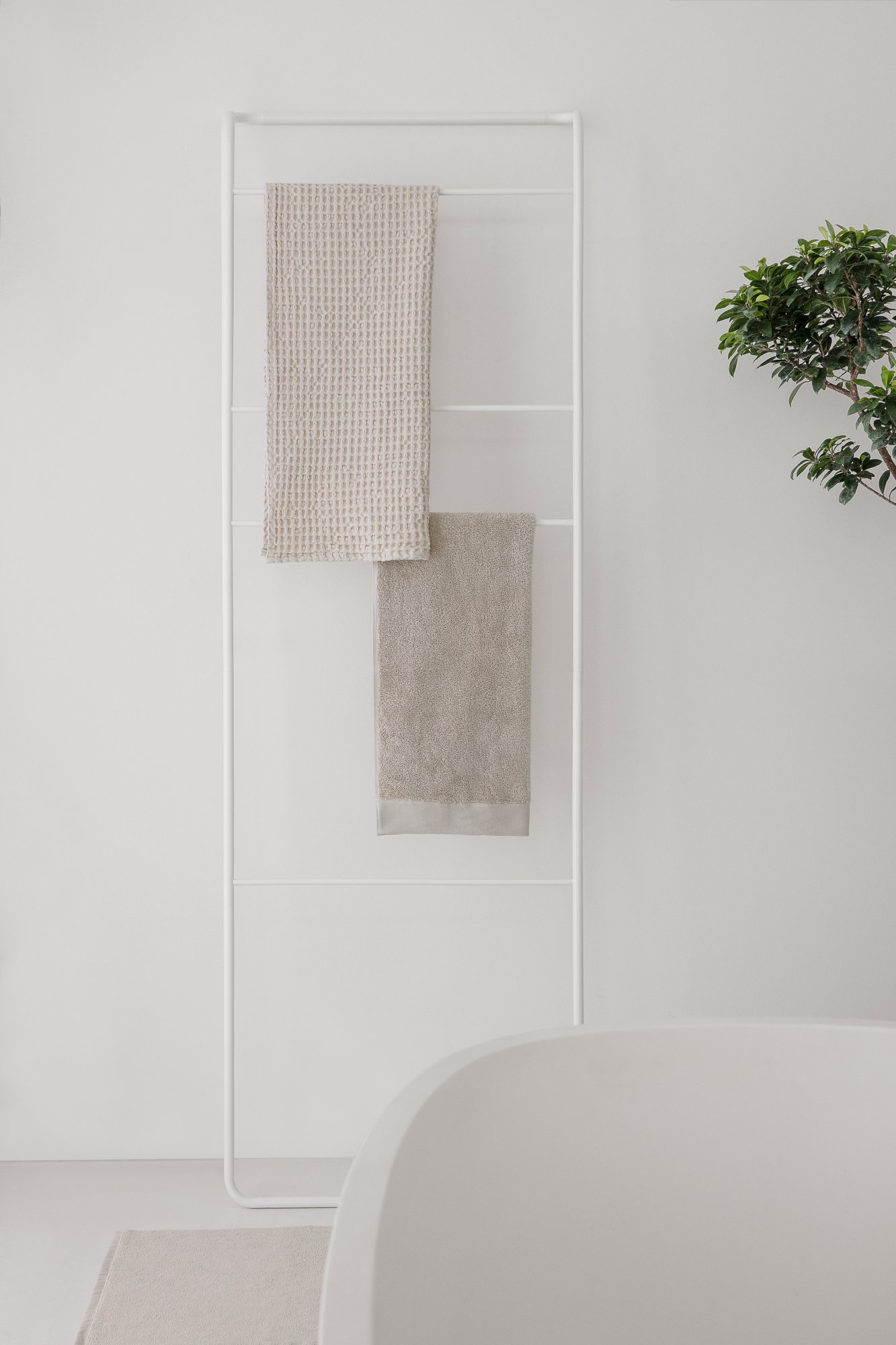 Neutral-toned towels hanging in a modern bathroom with minimalist decor.