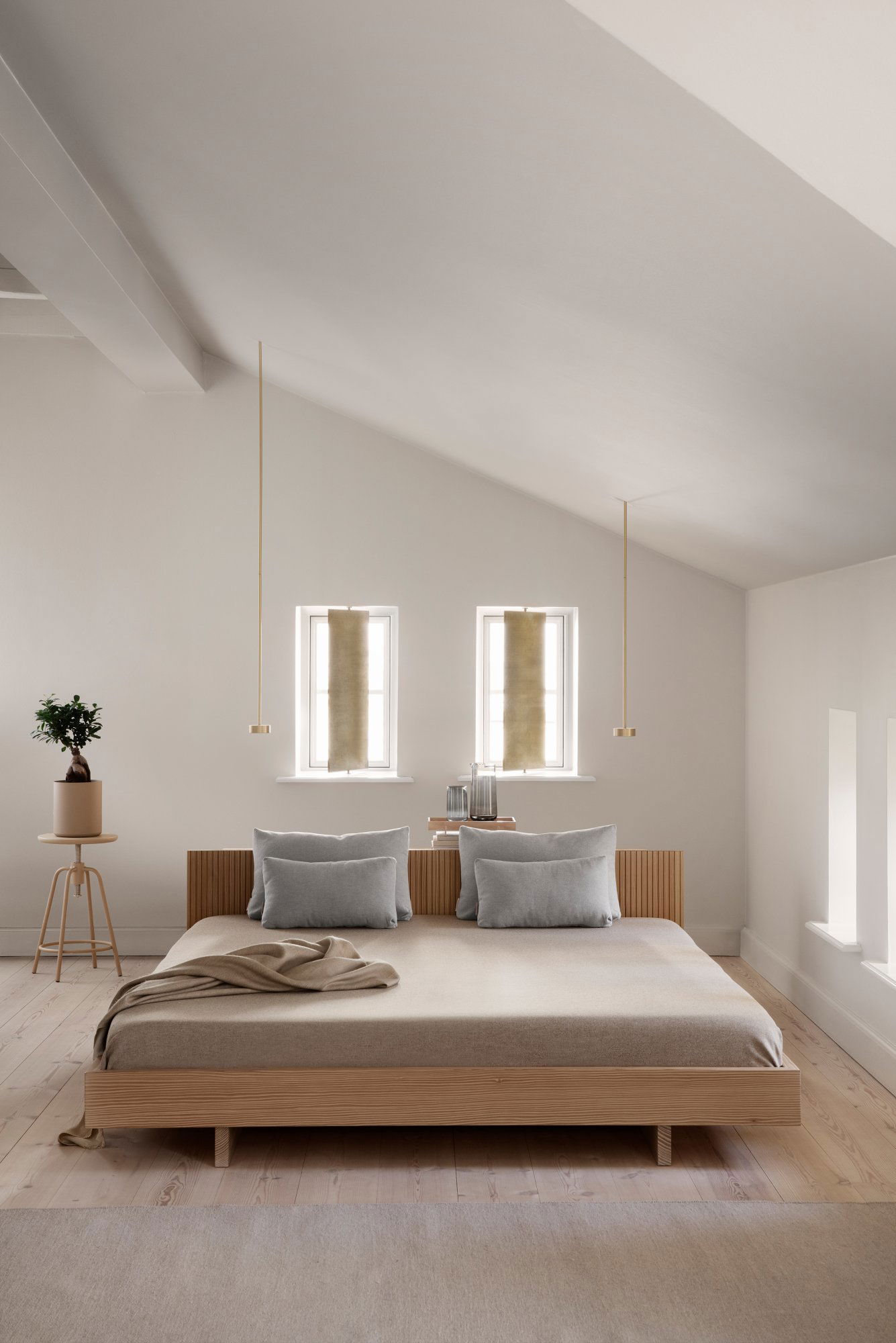 Modern minimalist bedroom with a wooden bed, soft decor, and natural light.
