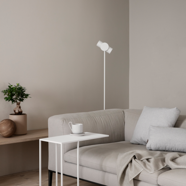 Modern living room with a minimalist couch, white side table, and decorative plants.