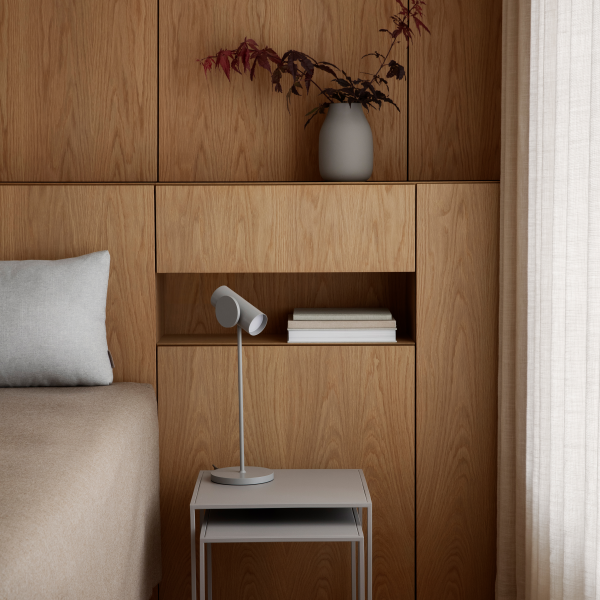 Modern bedroom decor featuring wood paneling, a minimalist lamp, and decorative vase.