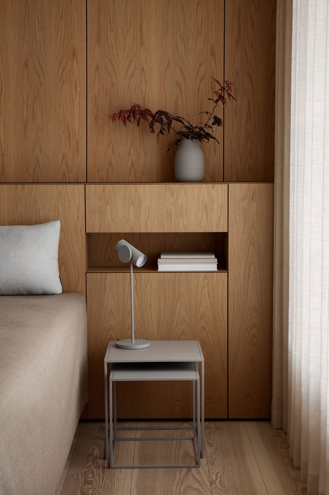 Modern bedroom decor featuring wood paneling, a minimalist lamp, and decorative vase.