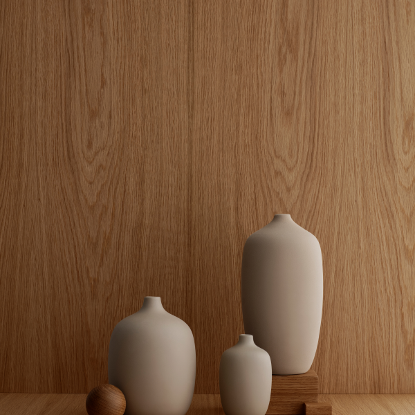 Modern ceramic vases in neutral tones displayed against a wooden background.