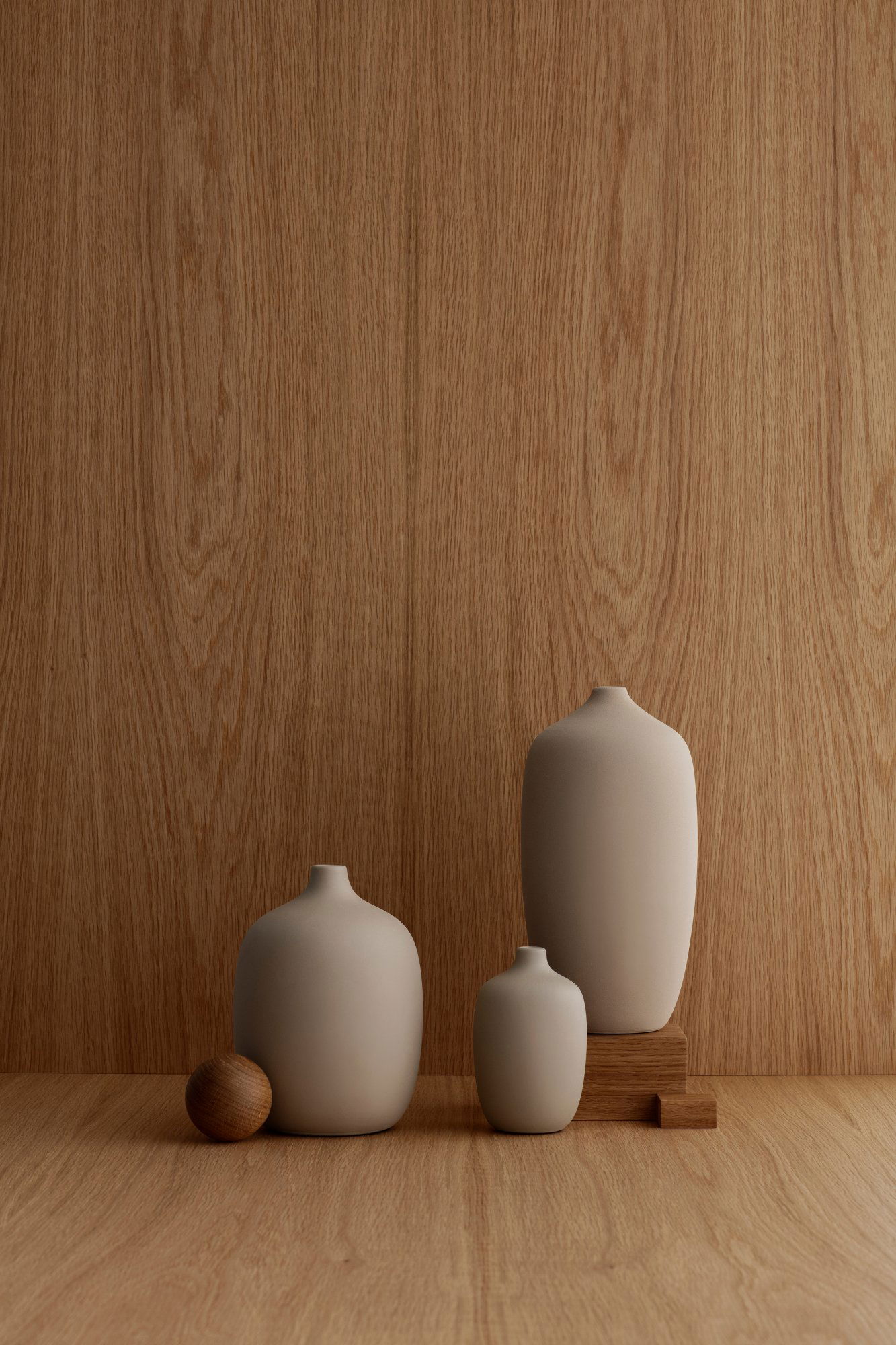 Modern ceramic vases in neutral tones displayed against a wooden background.