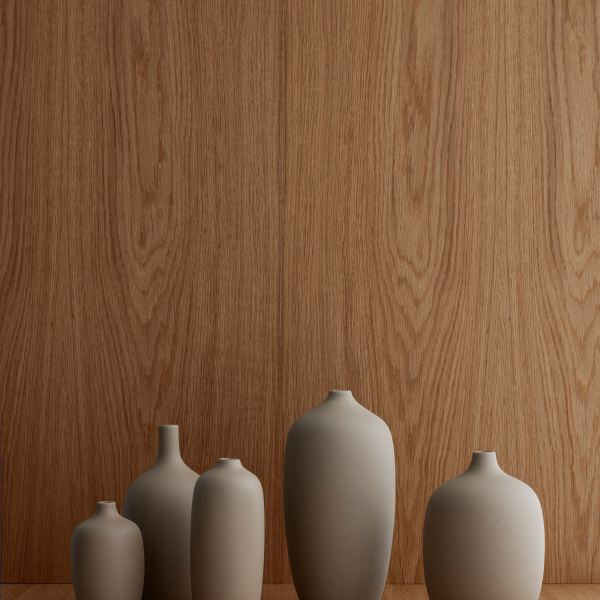 Minimalist vases in varying shapes against a textured wooden background.