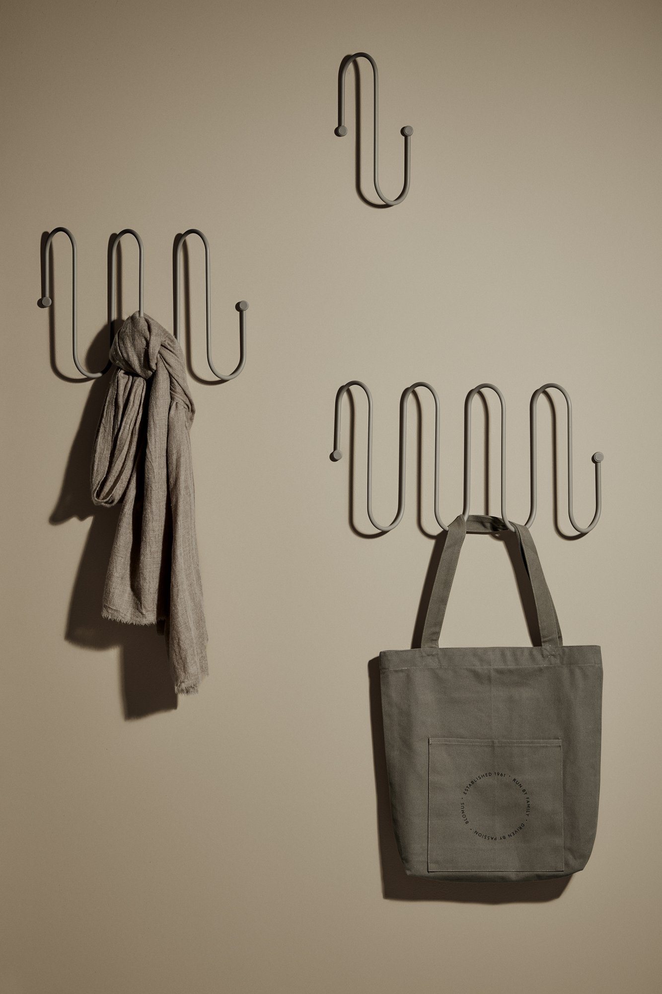 Stylische Wandhaken, die einen Schal und eine Tragetasche vor einem neutralen Hintergrund zeigen.