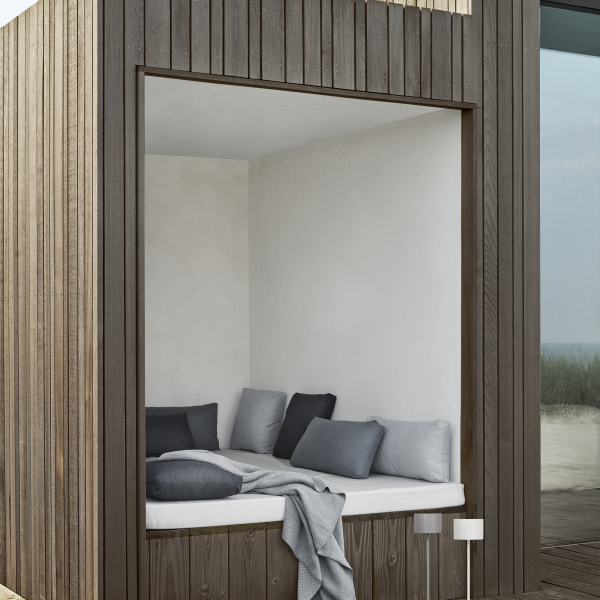 Cozy outdoor nook with soft cushions and a minimalist design by the seaside.