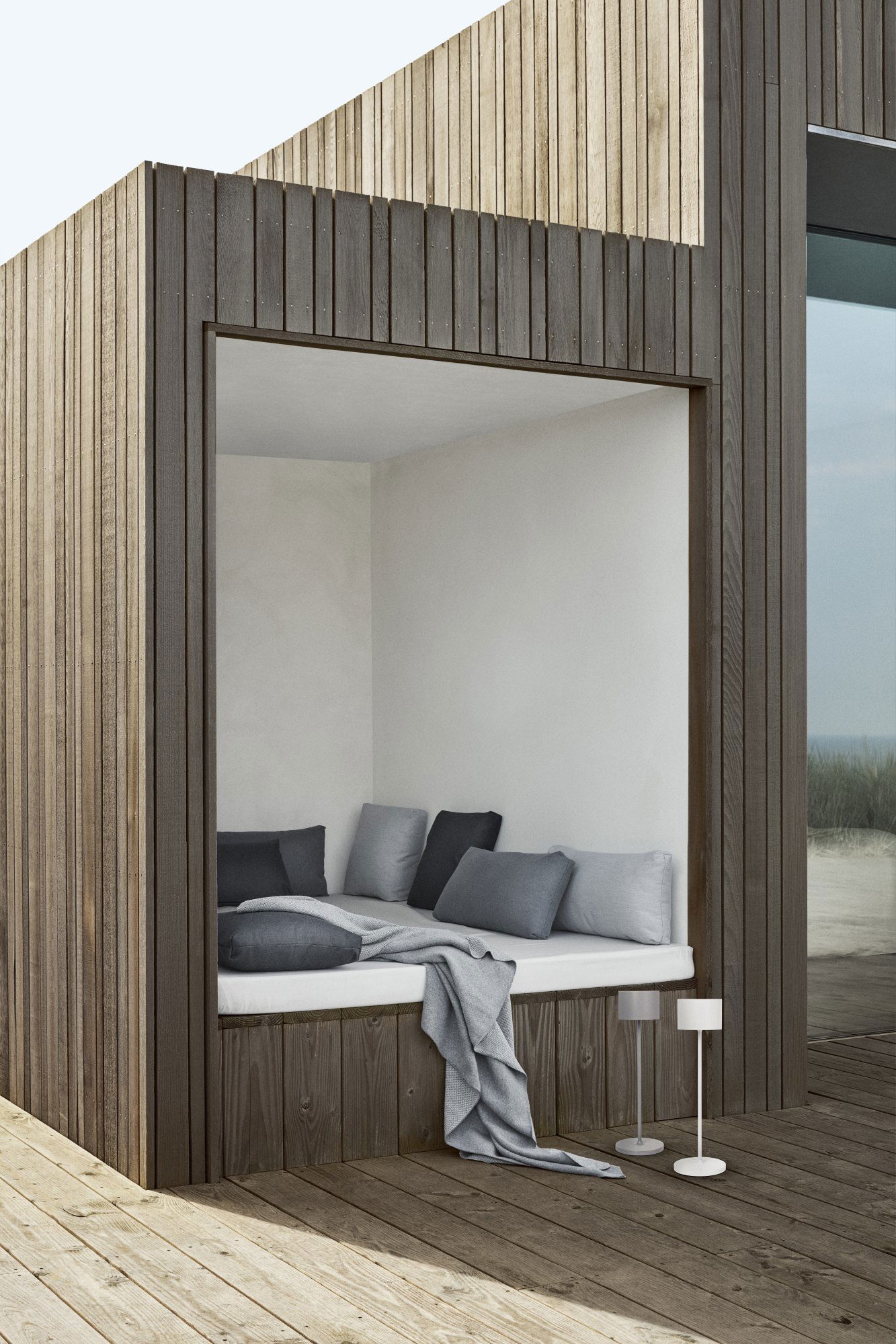 Cozy outdoor nook with soft cushions and a minimalist design by the seaside.