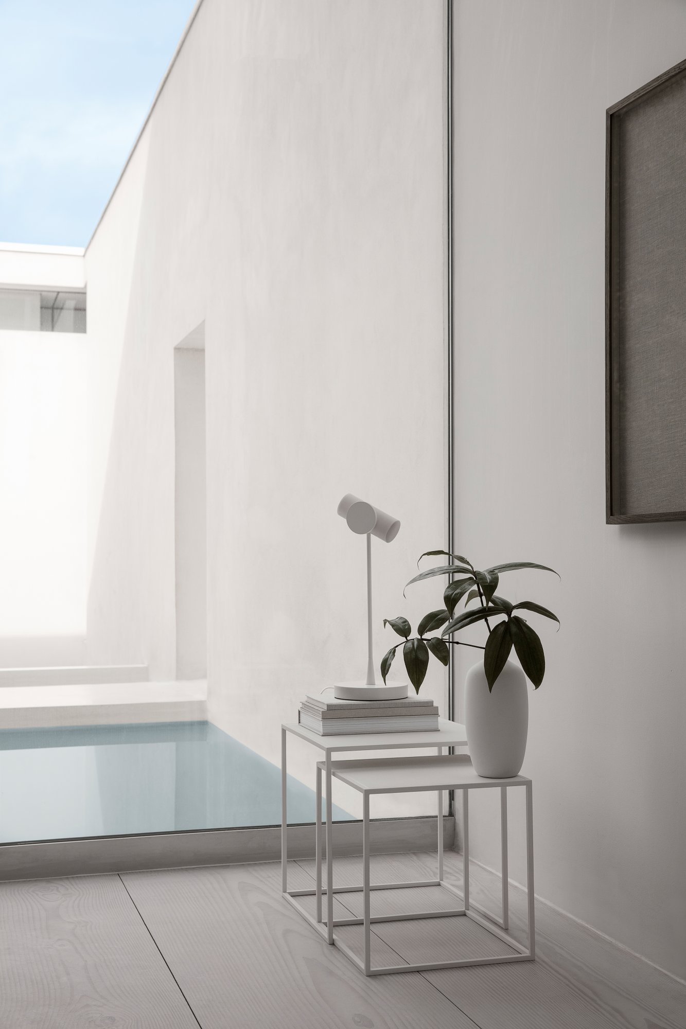 Modern minimalism featuring a white lamp and potted plant by a serene indoor pool.