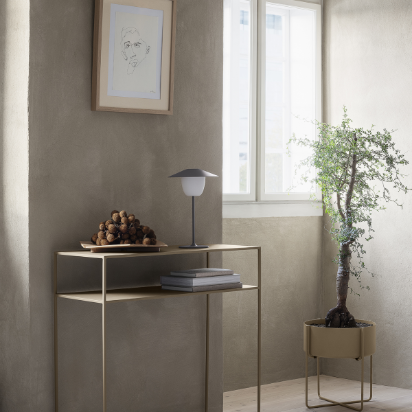 Stylish corner with a modern table, lamp, and decorative plant in a sunlit room.
