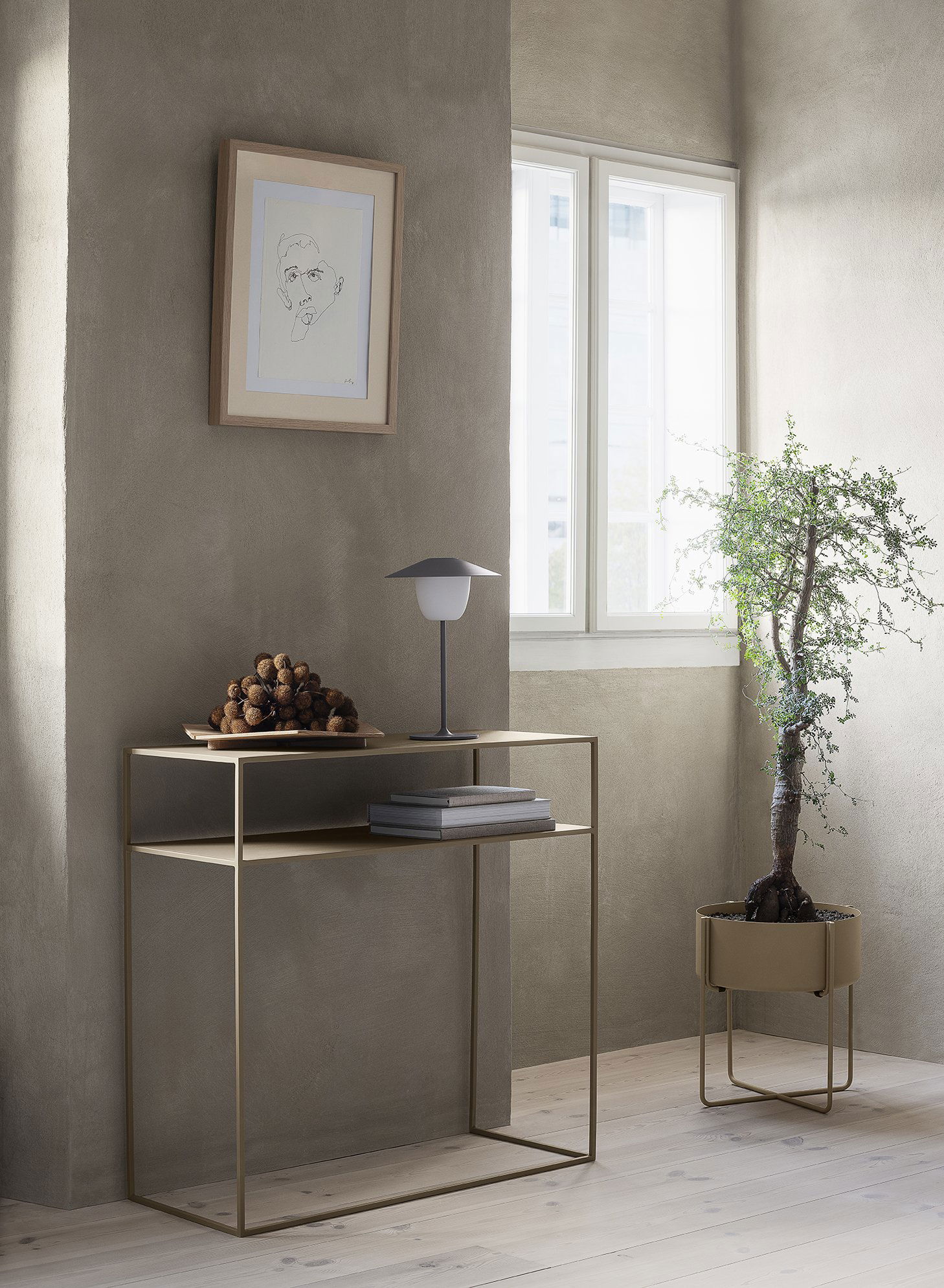 Stylish corner with a modern table, lamp, and decorative plant in a sunlit room.