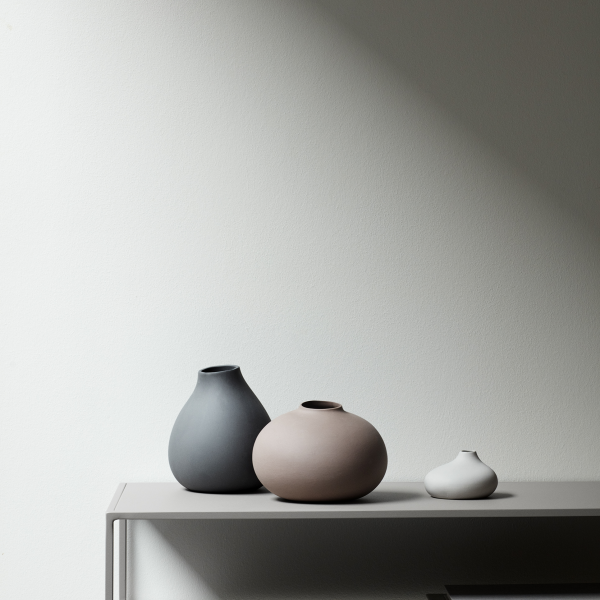 Elegant ceramic vases in neutral tones displayed on a minimalist shelf against a soft backdrop.