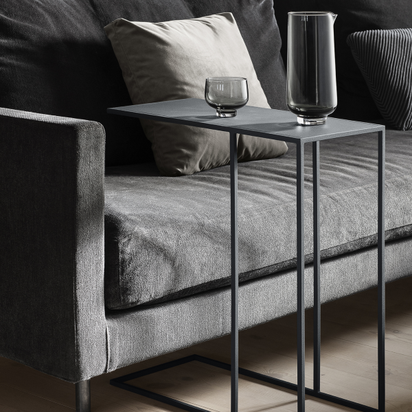 Moderner grauer Sofa mit stilvollem Beistelltisch und Glasbehältern in einem minimalistischen Innenraum.