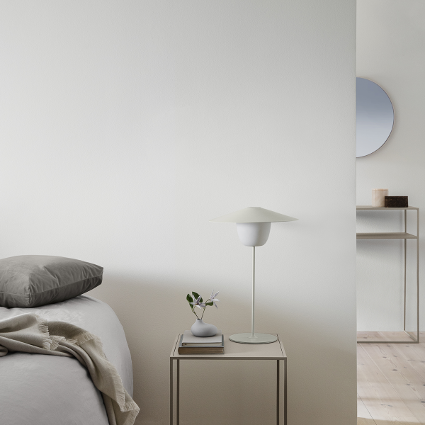 Moderne Schlafzimmerdekoration mit einer minimalistischen Lampe, neutralen Farbtönen und stilvollen Accessoires.