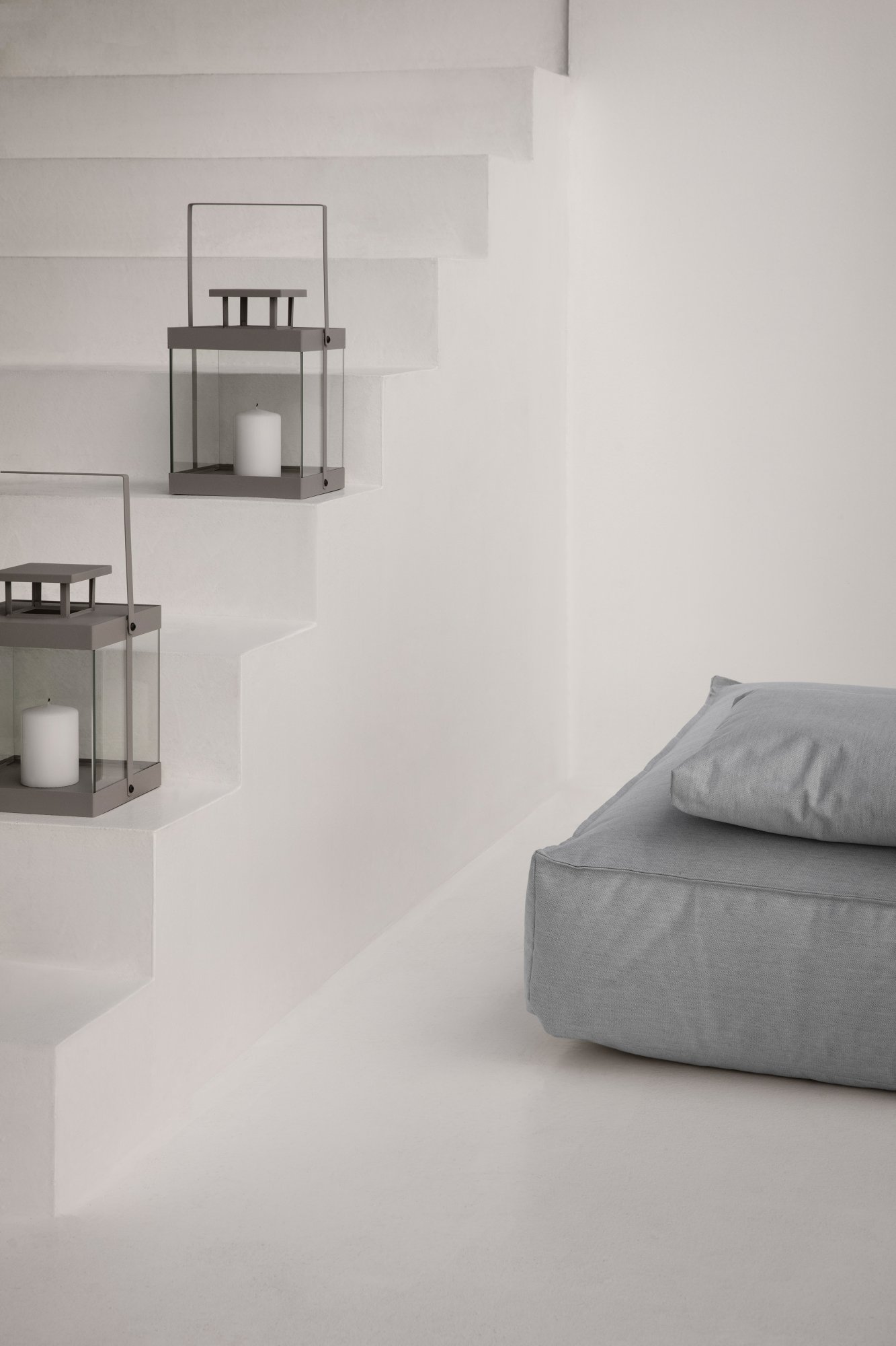 Cozy stairway with minimalist lanterns and a plush gray cushion for relaxation.