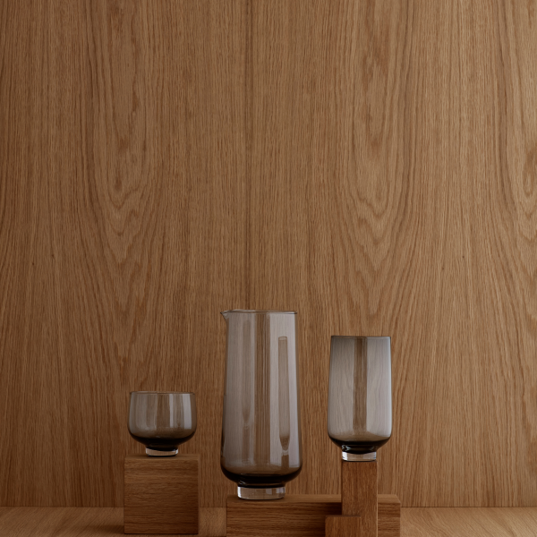 Elegantes Glaswaren-Set vor einem warmen Holz-Hintergrund, das moderne Designästhetik präsentiert.