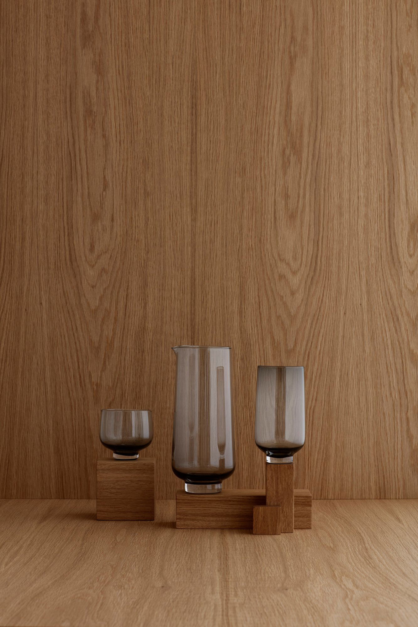 Elegantes Glaswaren-Set vor einem warmen Holz-Hintergrund, das moderne Designästhetik präsentiert.