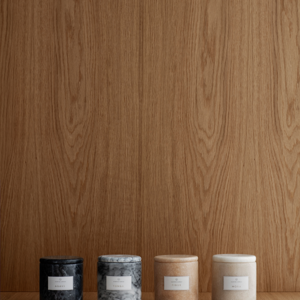 Elegante Duftkerzen in minimalistischen Behältern auf einem Holzuntergrund.