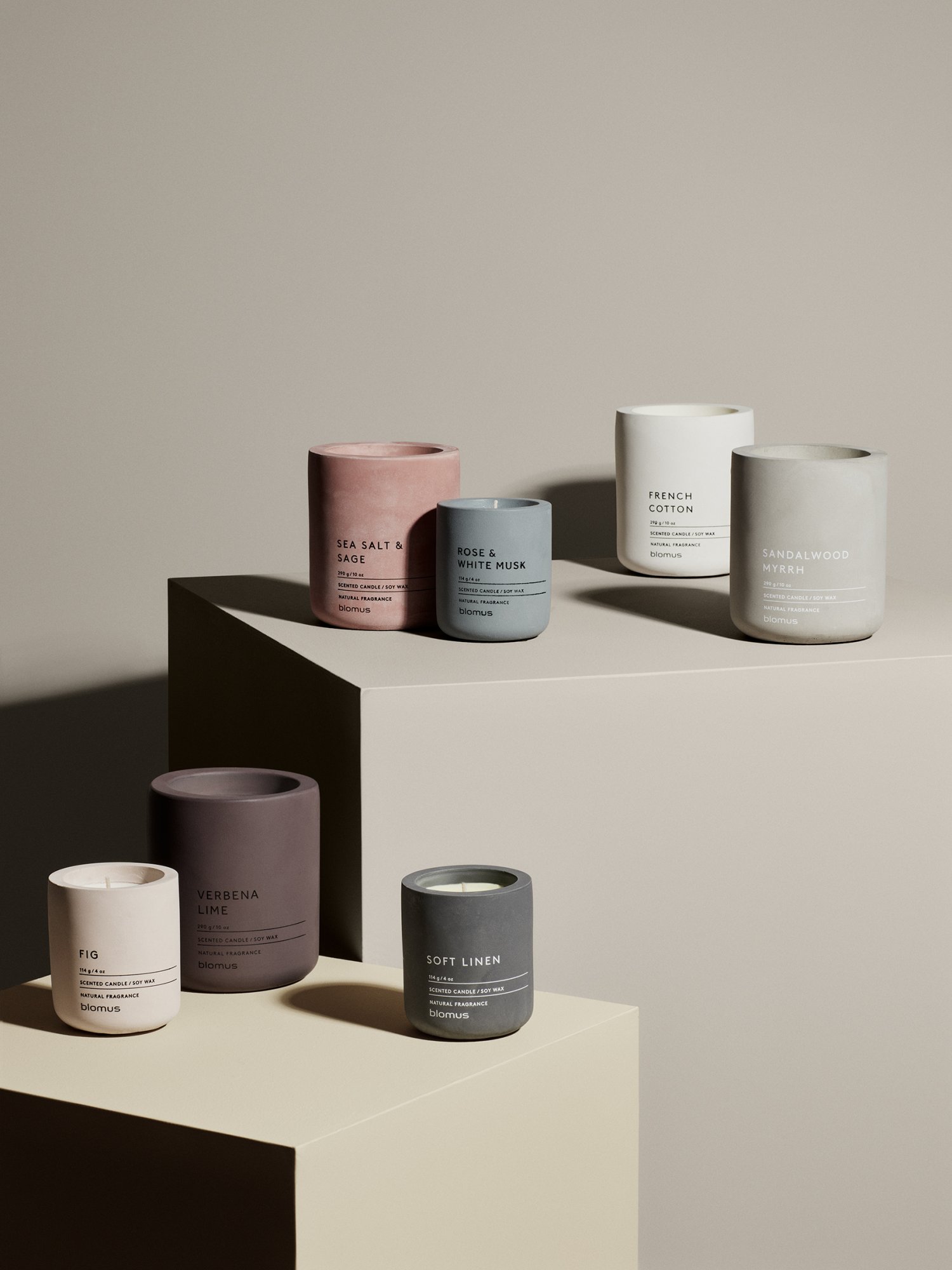 Stylish collection of scented candles in modern concrete containers on display.