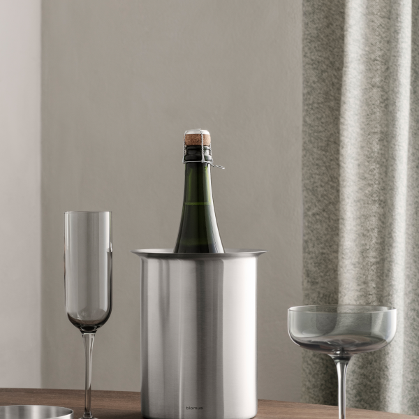 Schicke Champagnerflasche in einem Edelstahlkühler mit eleganten Gläsern in der Nähe.
