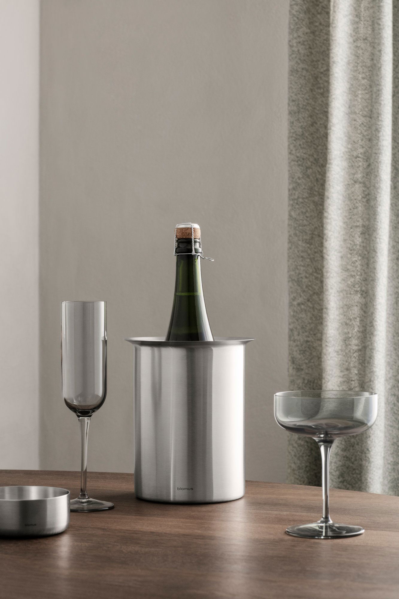 Schicke Champagnerflasche in einem Edelstahlkühler mit eleganten Gläsern in der Nähe.