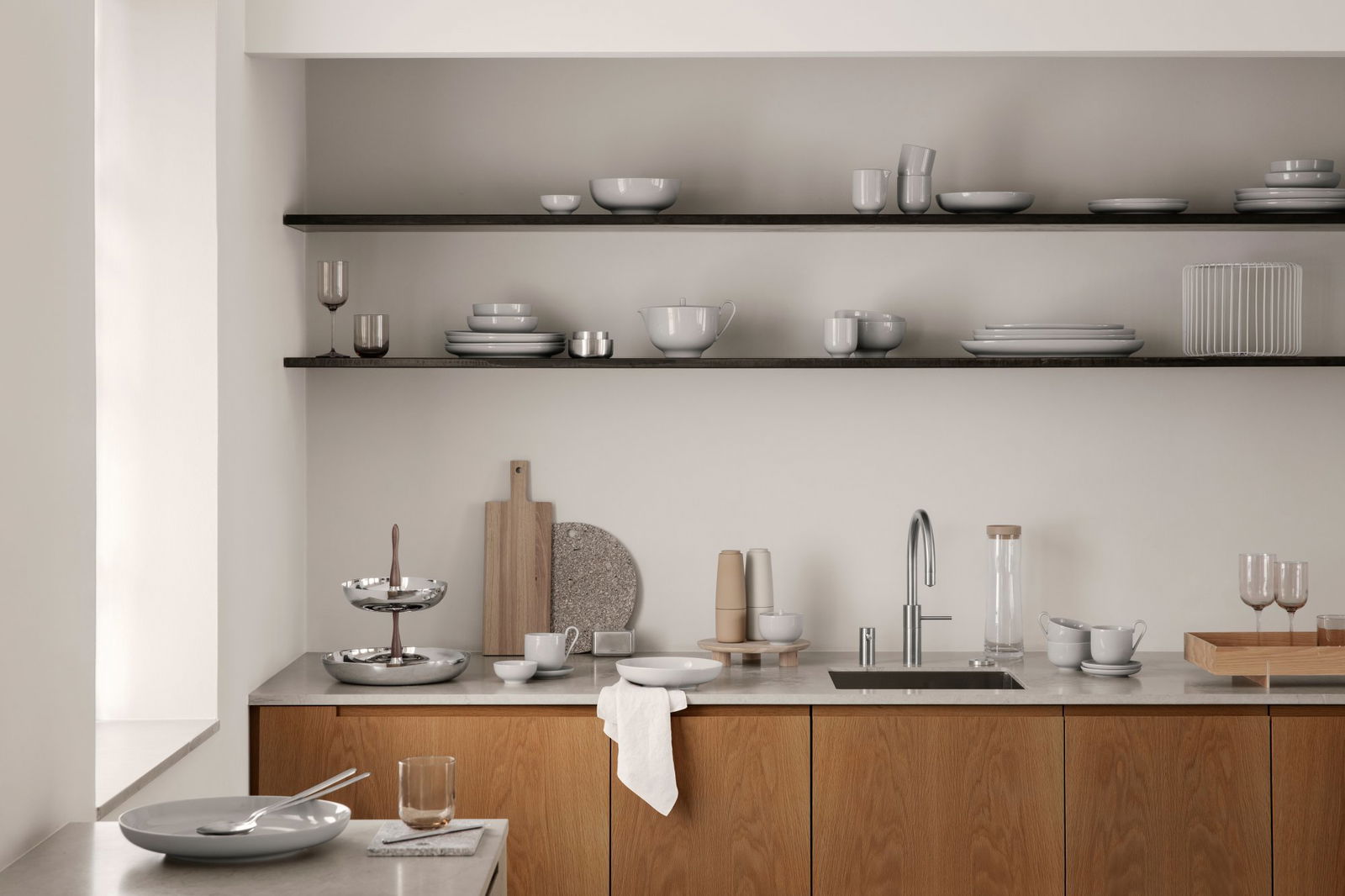 Minimalistische Küche mit Holzschränken, elegantem Geschirr und offenen Regalen.
