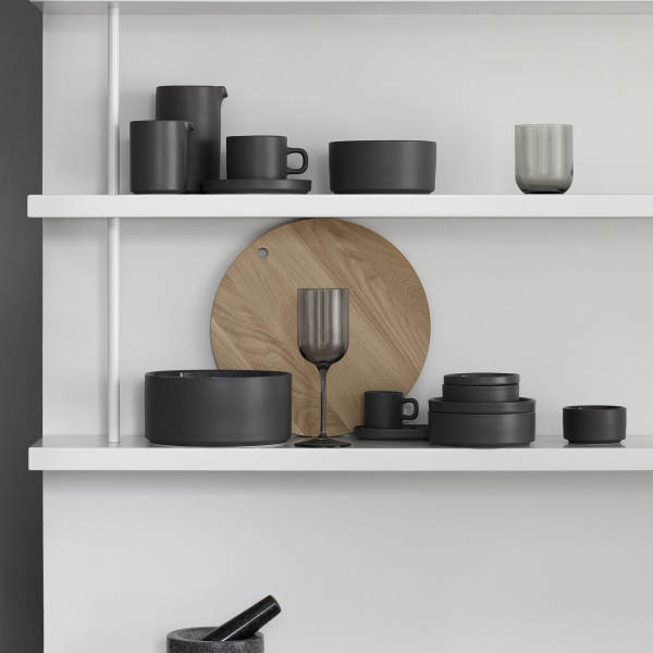Moderne schwarze Keramikteller auf einem minimalistischen weißen Regal mit einem Holzelement präsentiert.
