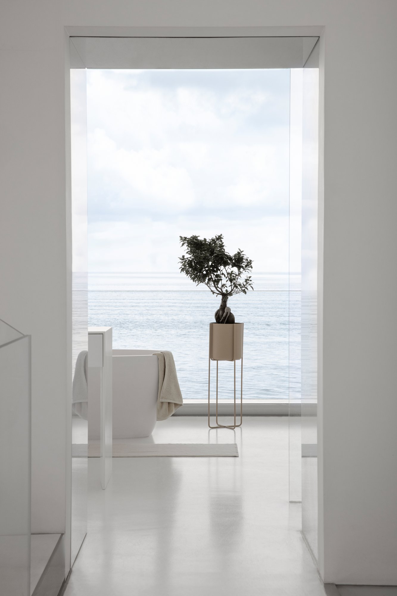 Modern bathroom with a view of the ocean featuring a potted plant and minimalist design.