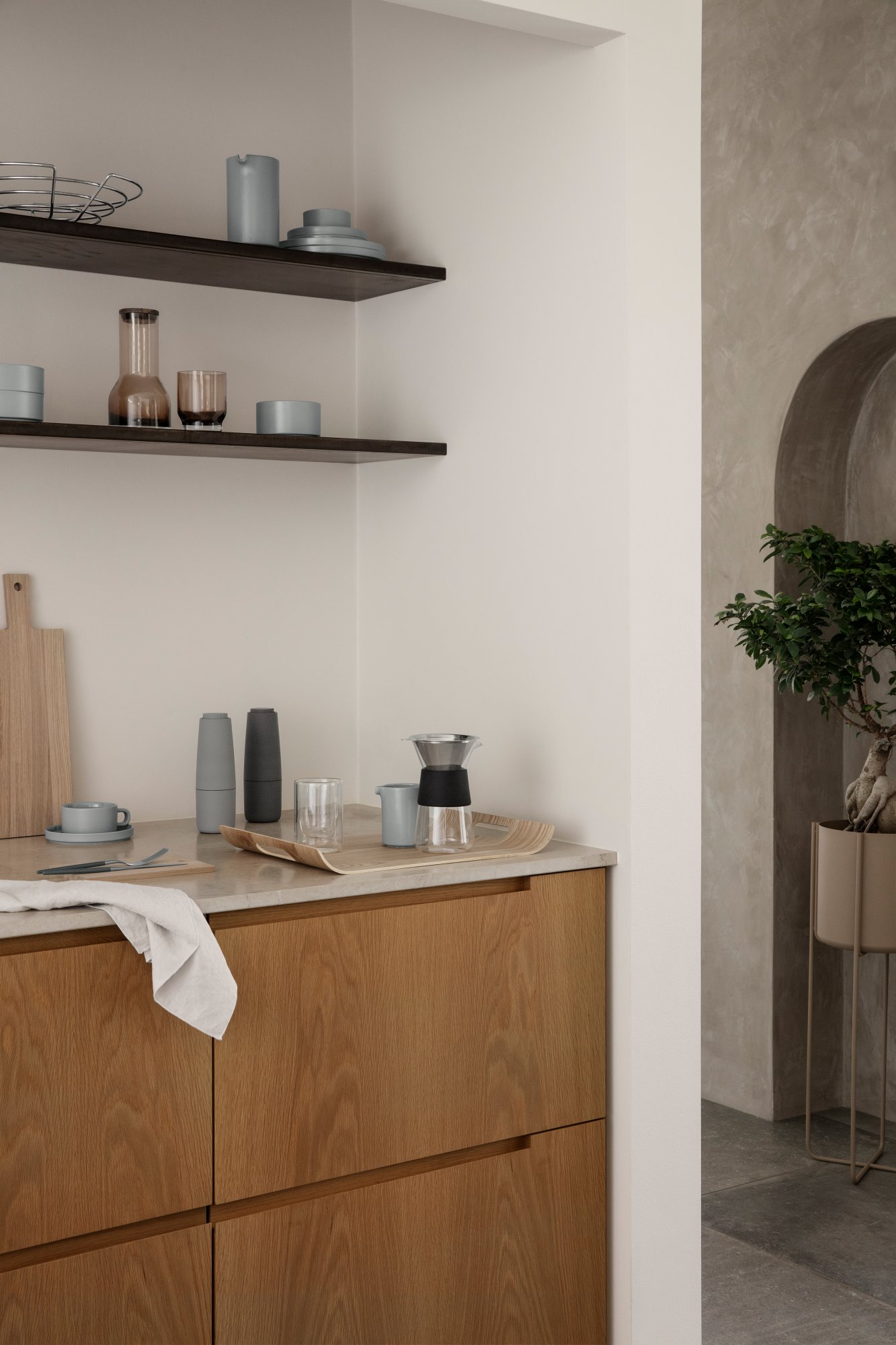 Modern kitchen decor featuring wooden cabinets, minimalist tableware, and stylish shelving.
