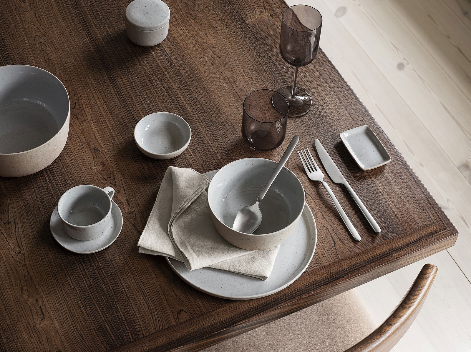 Elegant dining setup with minimalistic tableware on a wooden table.