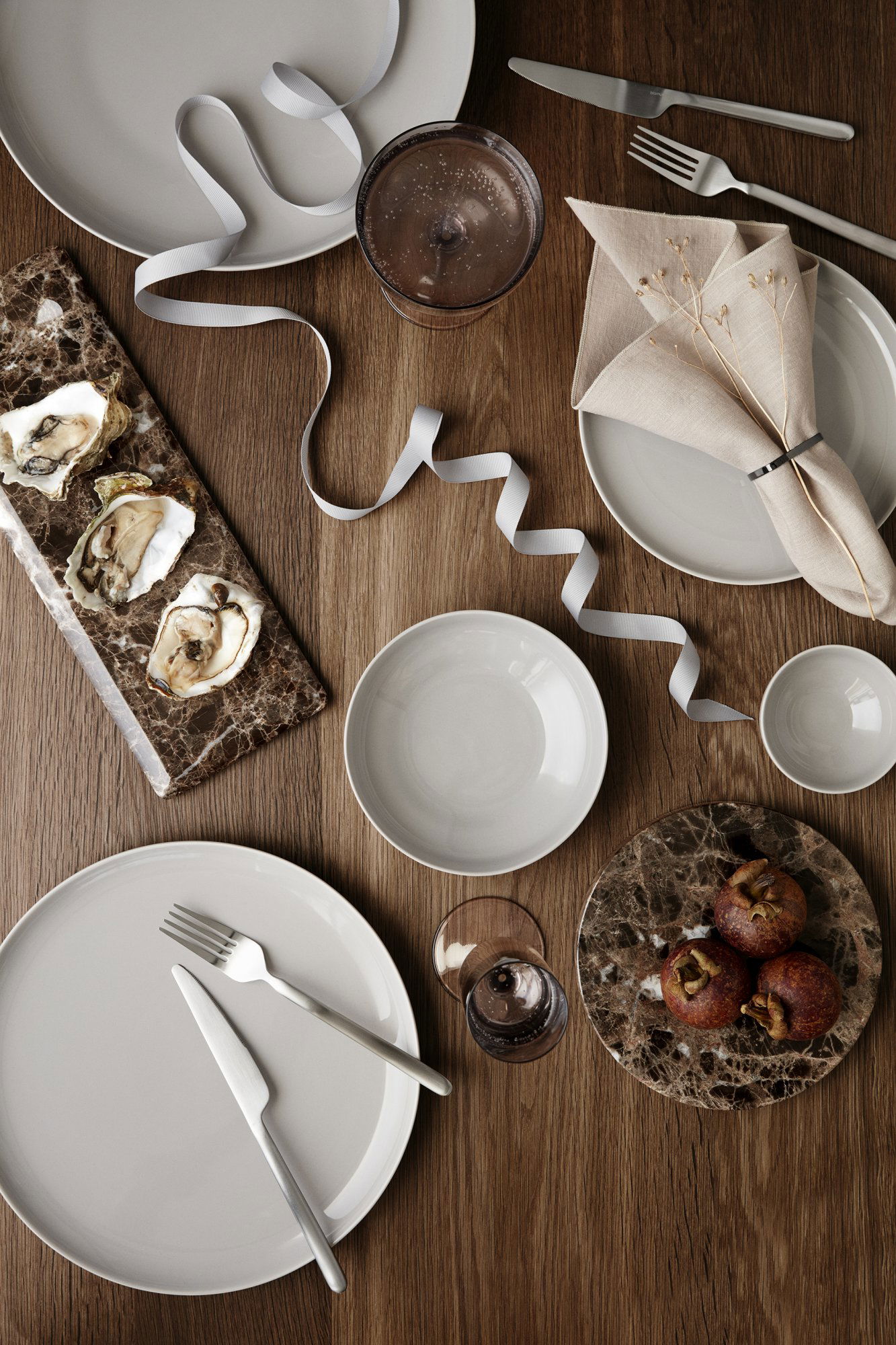 Elegant dining table setup with oysters, desserts, and refined tableware.