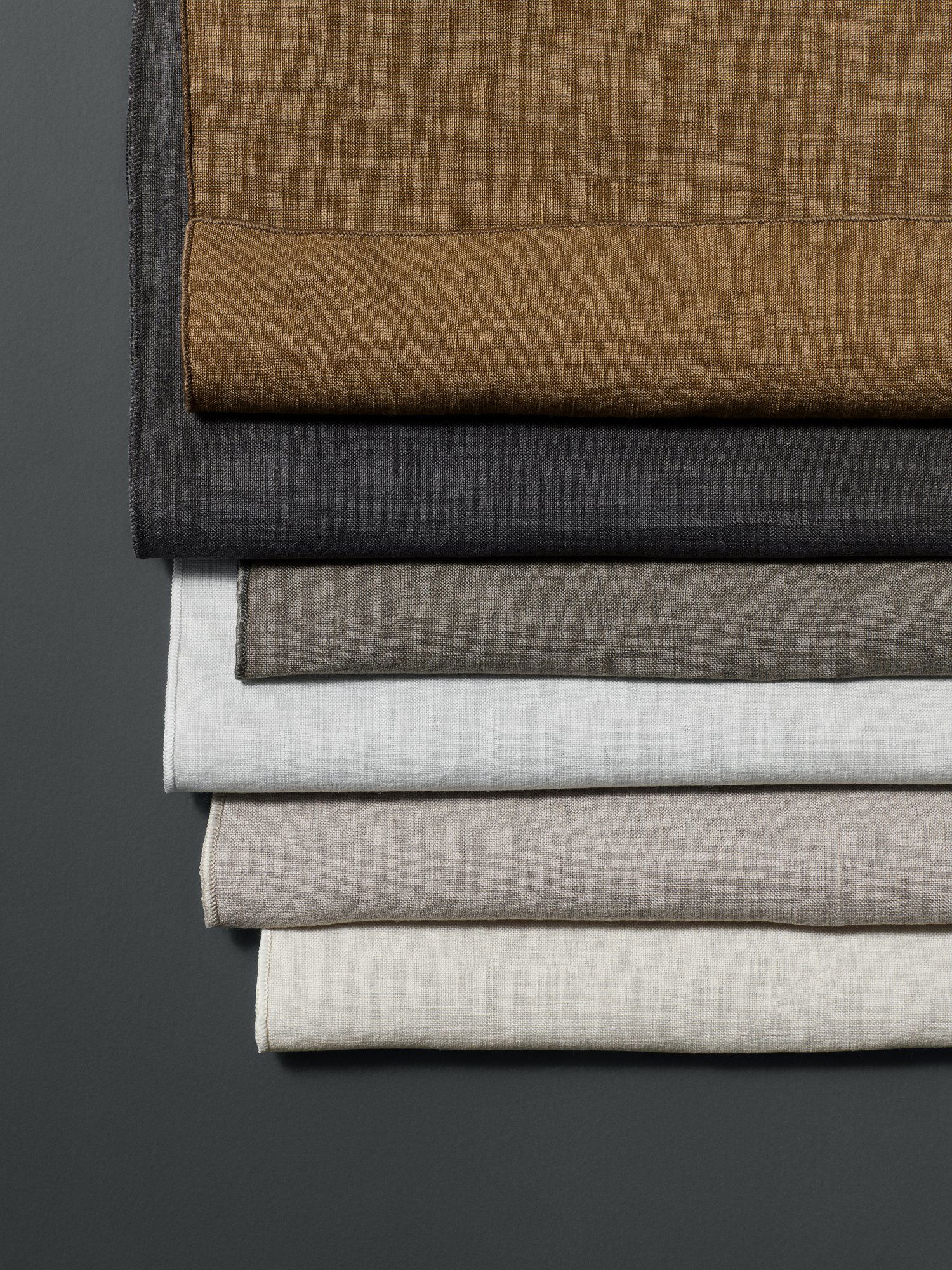 A stack of assorted linen fabric pieces in various neutral colors.
